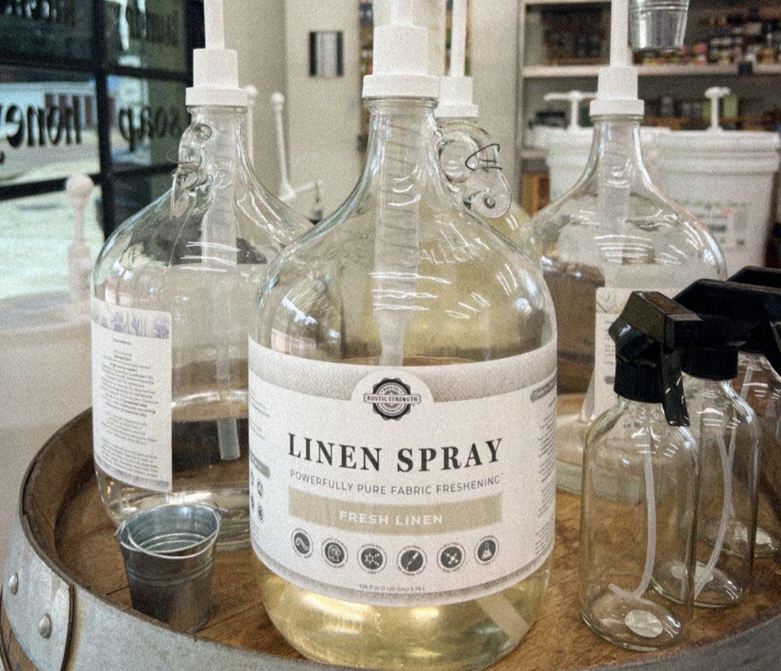 Gallon refill jugs of linen spray with pumps on the barrel inside the shop
