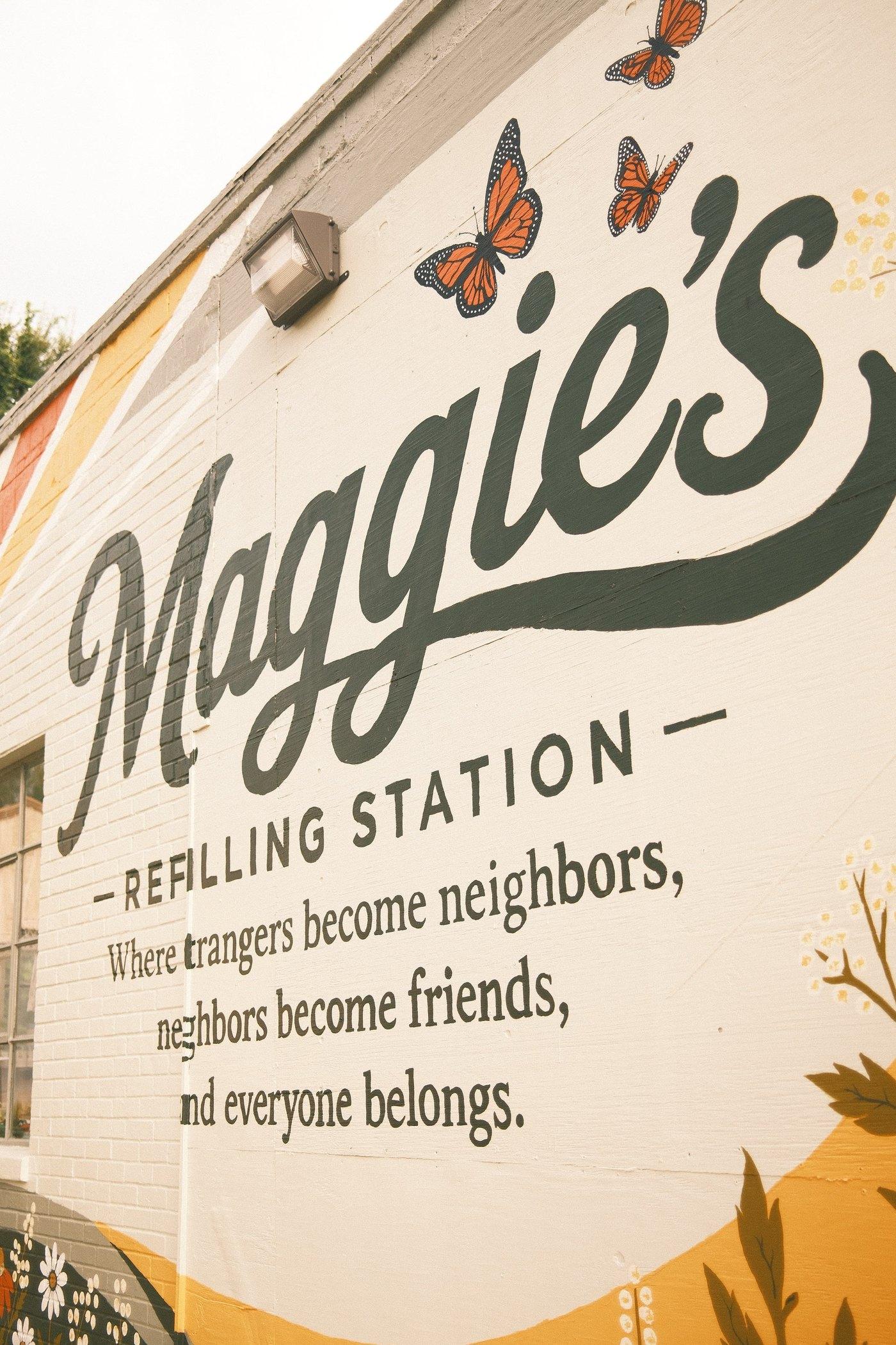 The hand-painted wall at Maggie's Re-Filling Station on Main Street: “Where strangers become neighbors, neighbors become friends, and everyone belongs.”